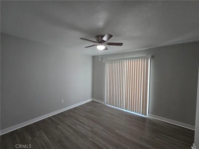 an empty room with wooden floor closet and windows