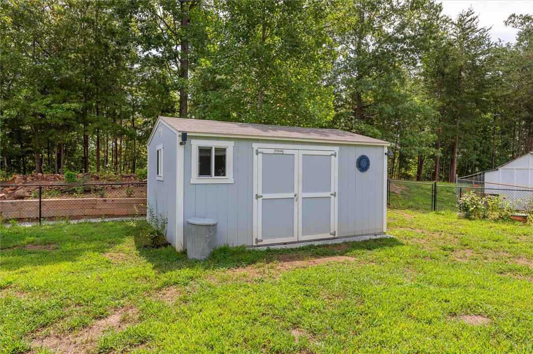67 Sawblade Ridge Marietta, SC 29661 - Photo 25 of 37 A quaint shed offers practical storage amidst a verdant, fenced yard.