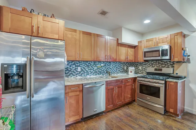 a kitchen with stainless steel appliances granite countertop a stove a sink and a refrigerator