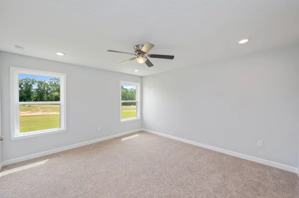an empty room with windows and ceiling fan