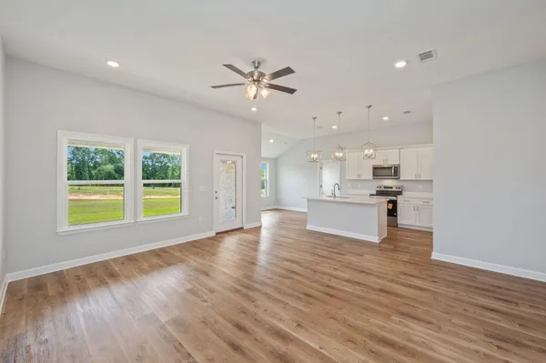 a view of an empty room with a kitchen and wooden floor