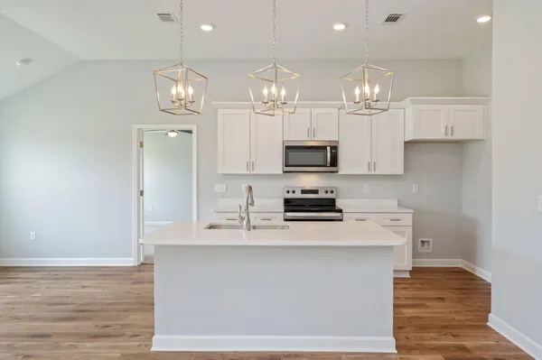 a kitchen with kitchen island granite countertop a sink cabinets and stainless steel appliances
