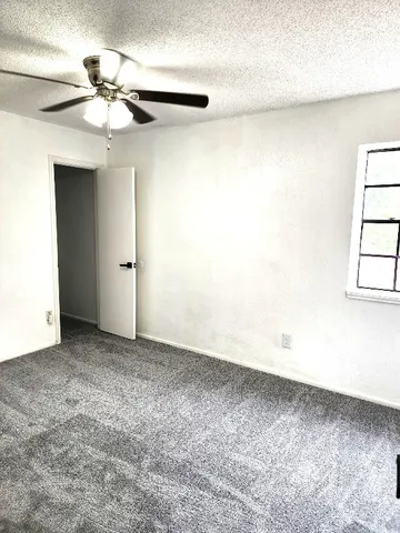 an empty room with a ceiling fan and a window