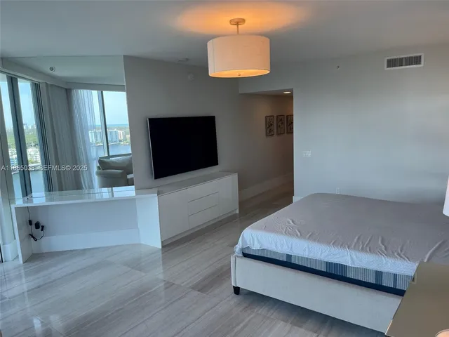 a bedroom with a bed and a flat tv screen on the dresser