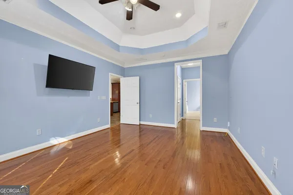 an empty room with wooden floor and chandelier fan