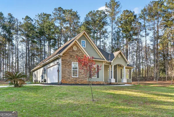 a front view of a house with a garden and trees