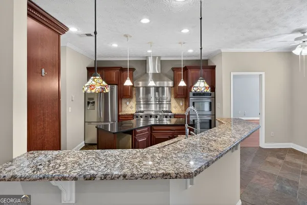 a kitchen with kitchen island granite countertop wooden cabinets and refrigerator