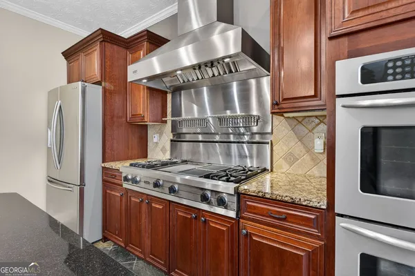 a kitchen with stainless steel appliances granite countertop a stove and a refrigerator