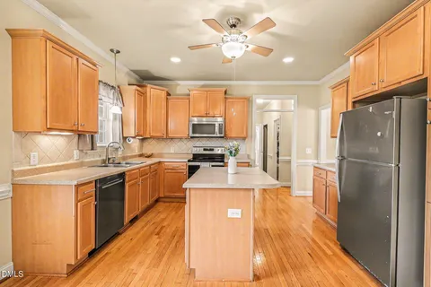 a large kitchen with stainless steel appliances granite countertop a refrigerator a sink dishwasher a stove with wooden cabinets and floor