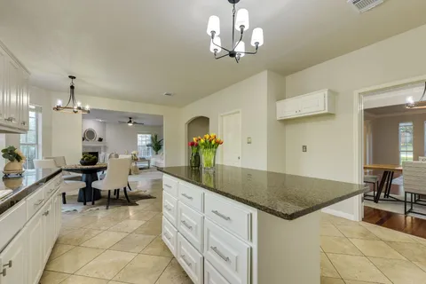 a large kitchen with kitchen island a chandelier a dining table and chairs