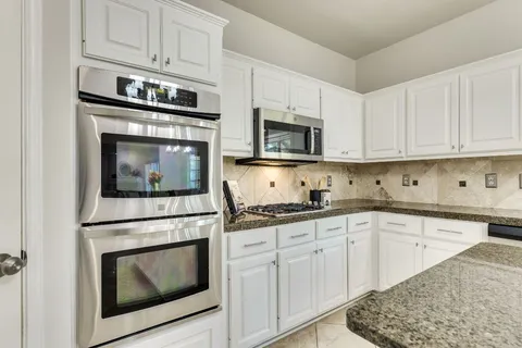 a kitchen with granite countertop white cabinets stainless steel appliances and a sink