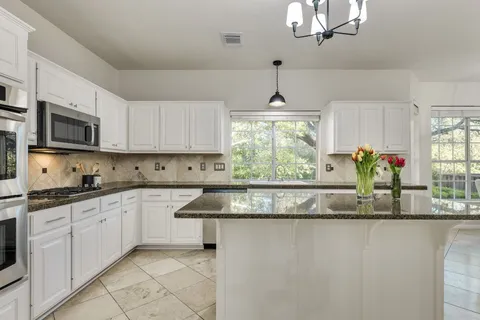 a kitchen with stainless steel appliances granite countertop a sink a stove and a granite counter tops