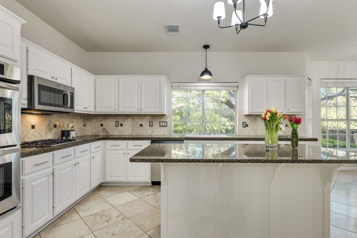 10701 Redmond Road Austin, TX 78739 - Photo 6 of 39 a kitchen with stainless steel appliances granite countertop a sink a stove and a granite counter tops