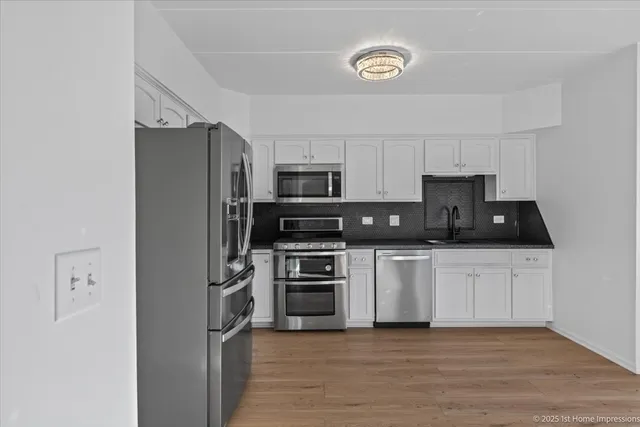 a kitchen with granite countertop a refrigerator a stove top oven a sink and dishwasher