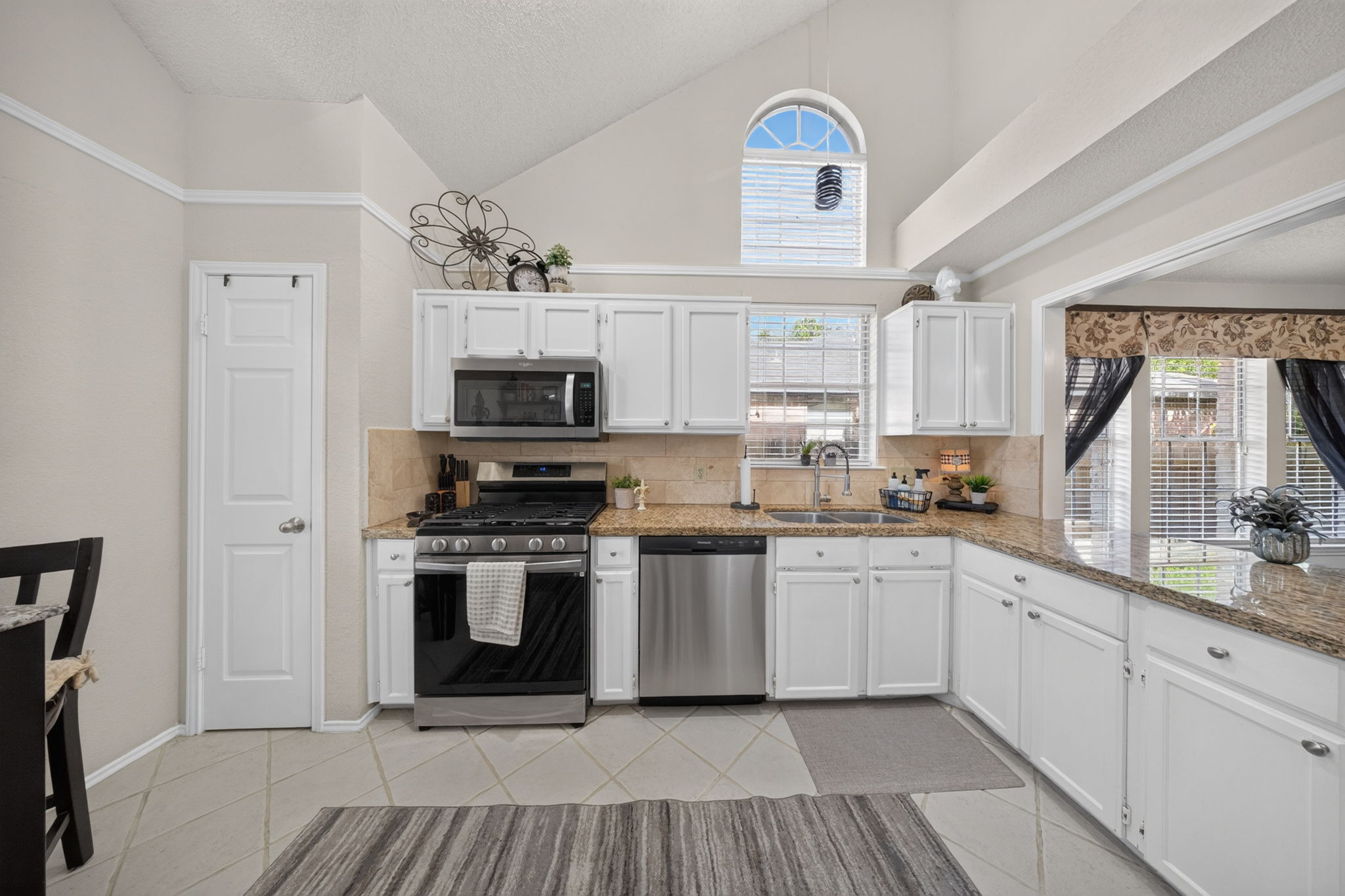 806 Mountain Ridge Drive Leander, TX 78641 - Photo 18 of 40 Vaulted ceilings soar over granite countertops and white cabinetry in this well-appointed kitchen.
