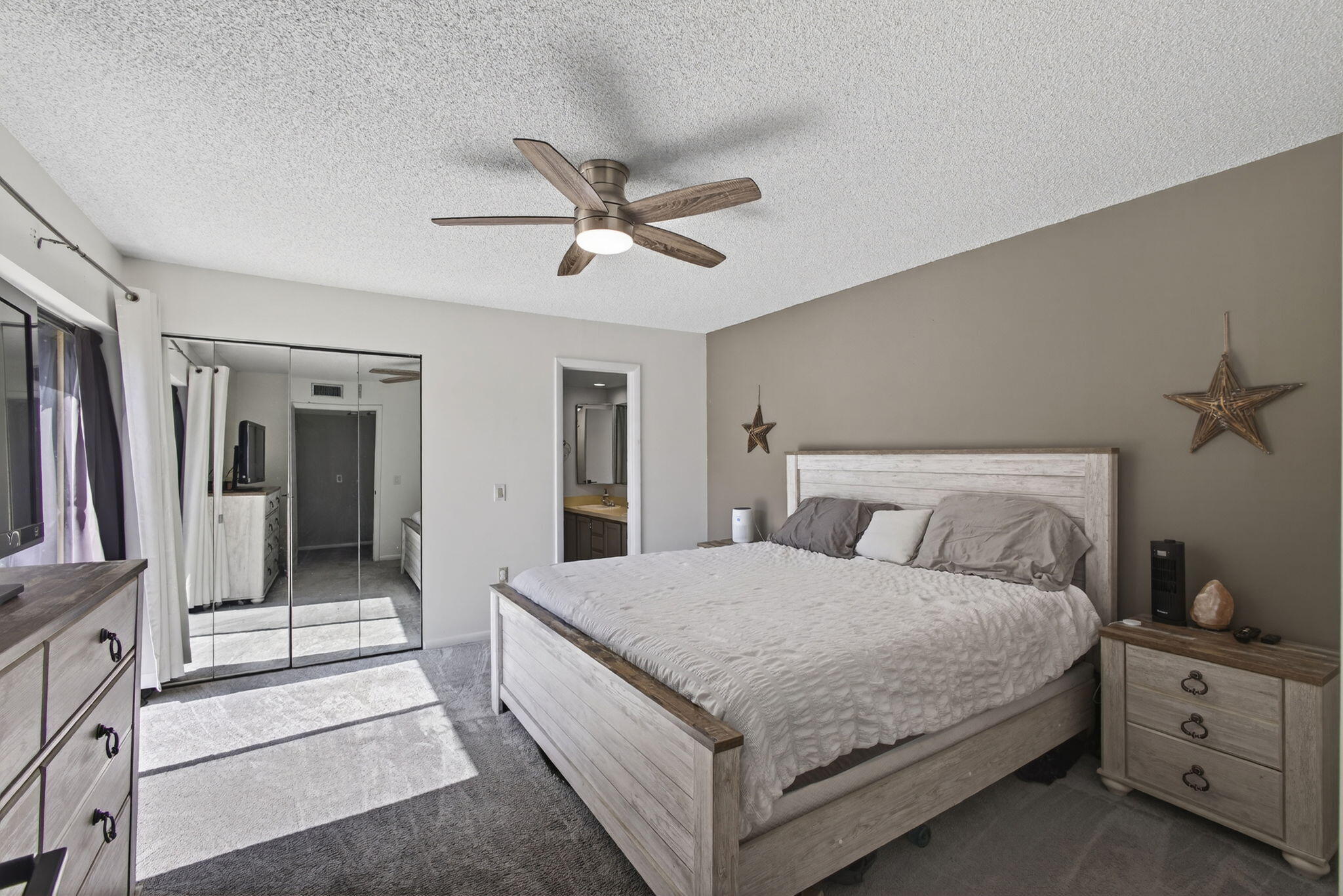 5680 Southeast Windsong Lane, Unit 345 Stuart, FL 34997 - Photo 25 of 54 a bedroom with a large bed and a chandelier