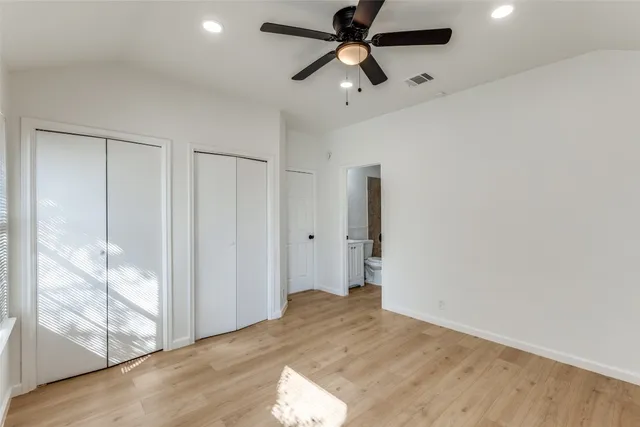 an empty room with wooden floor fan and windows