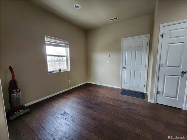 an empty room with wooden floor and windows
