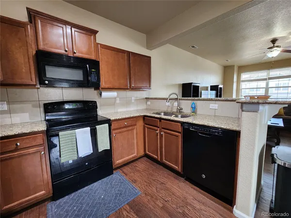 a kitchen with granite countertop a refrigerator stove top oven and sink