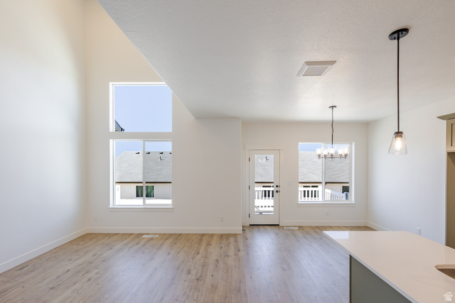 4752 Heartwood Road, Unit 433 Mapleton, UT 84664 - Photo 10 of 20 Unfurnished living room featuring a chandelier, light wood-style floors, and a high ceiling