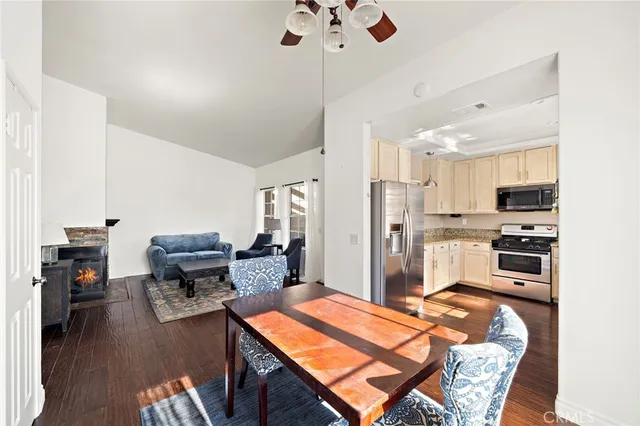 a kitchen with stainless steel appliances kitchen island granite countertop a refrigerator oven stove a dining table and chairs with wooden floor