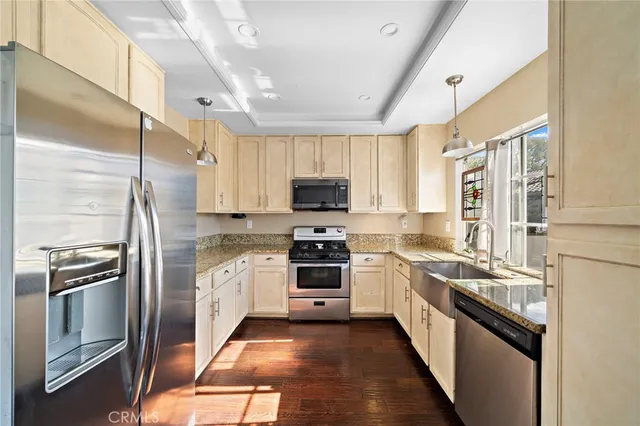 a kitchen with stainless steel appliances granite countertop a stove top oven a sink and a refrigerator