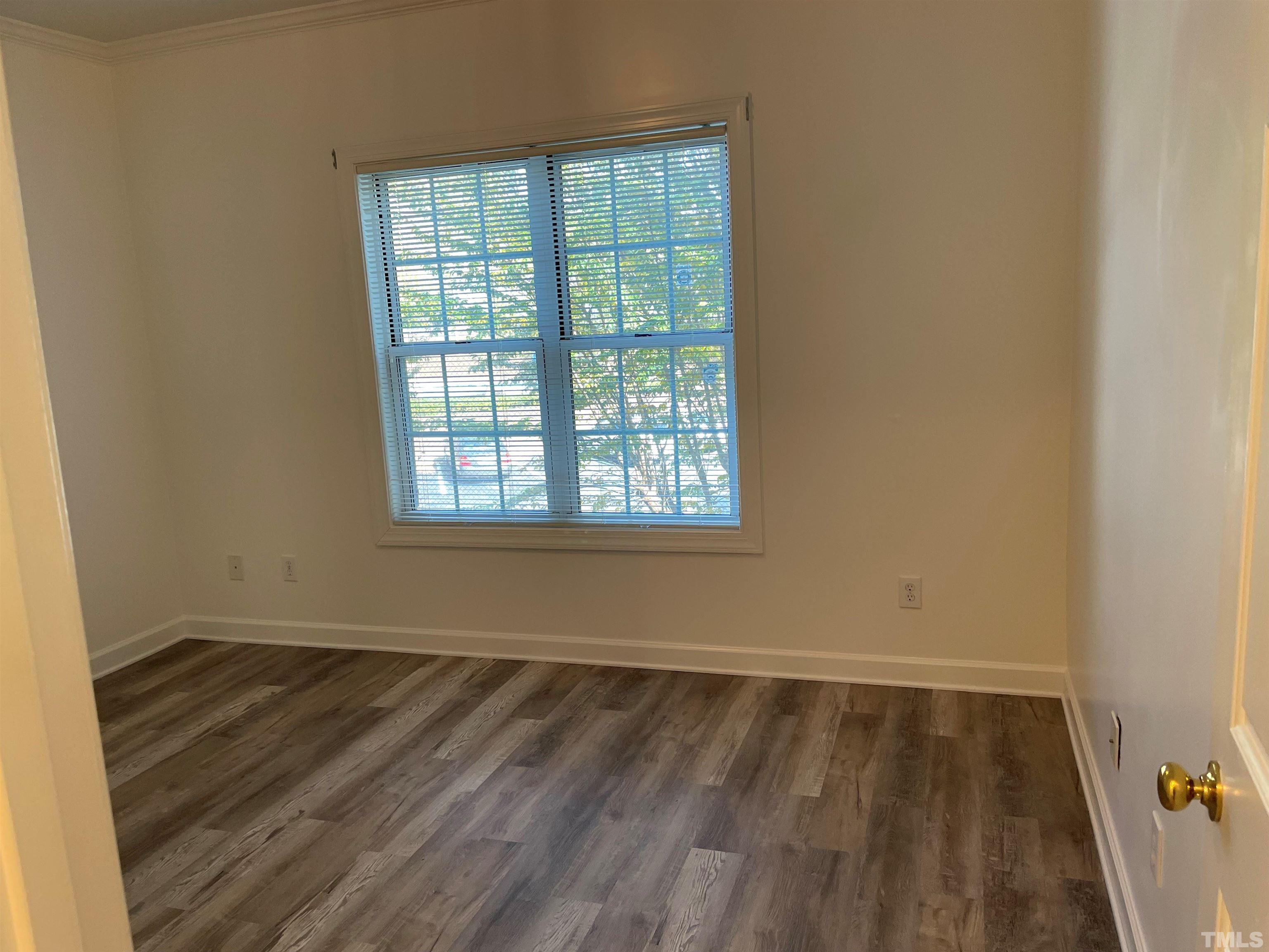 7018 Sandy Forks Road, Unit 202 Raleigh, NC 27615 - Photo 4 of 22 an empty room with wooden floor and windows