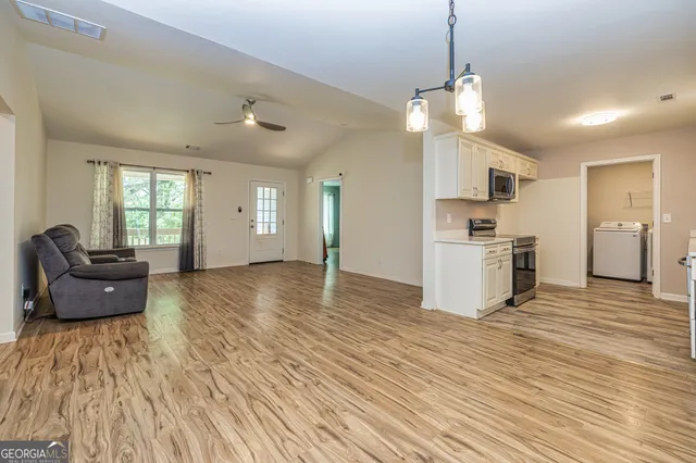 a view of an empty room with window and chandelier fan