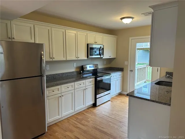 a kitchen with granite countertop a refrigerator stove top oven and sink