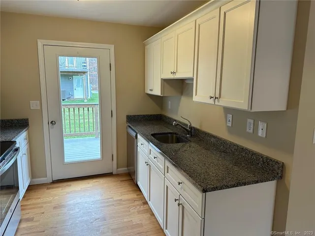 a kitchen with granite countertop white cabinets and a stove