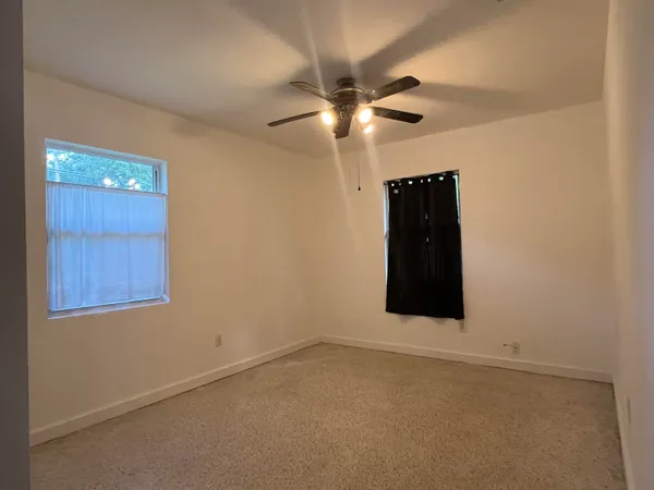 en empty room with windows and fan