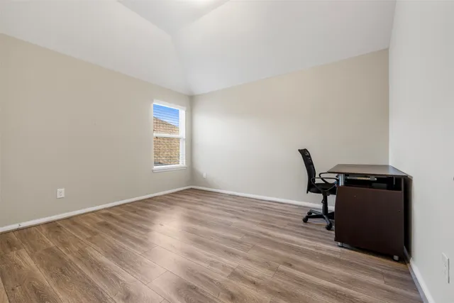a view of a workspace with wooden floor and a window