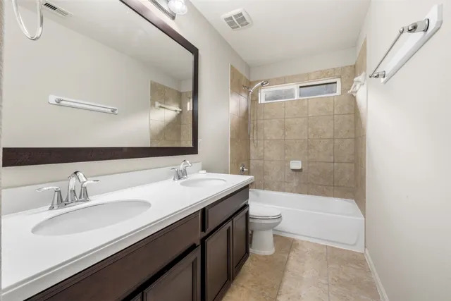 a bathroom with a double vanity sink toilet mirror and bathtub