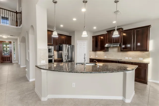 a kitchen with stainless steel appliances granite countertop a sink a stove and a refrigerator