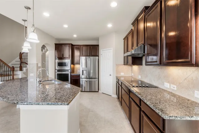 a kitchen with stainless steel appliances granite countertop a sink a stove and a refrigerator