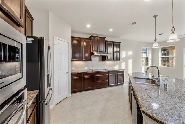 a large kitchen with stainless steel appliances granite countertop a stove and a sink