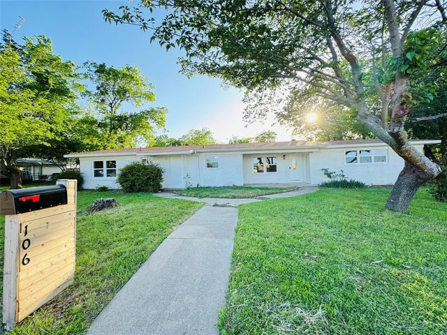 a front view of a house with garden and tree