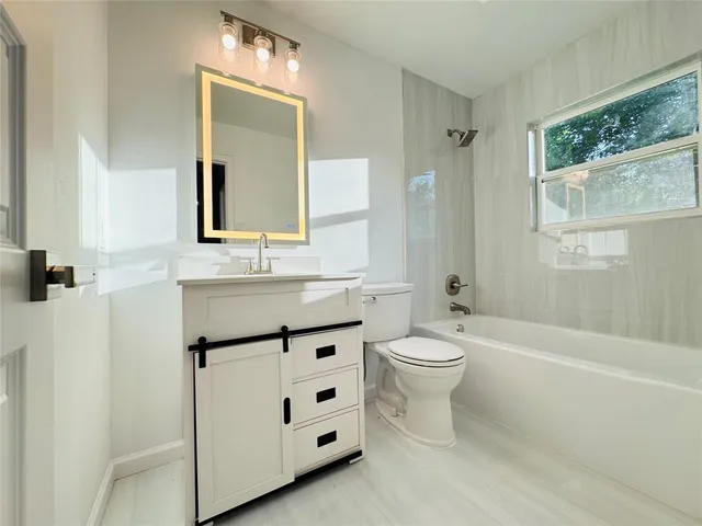 a bathroom with a toilet a sink a mirror and a bathtub