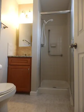 a bathroom with a granite countertop shower a mirror and a toilet