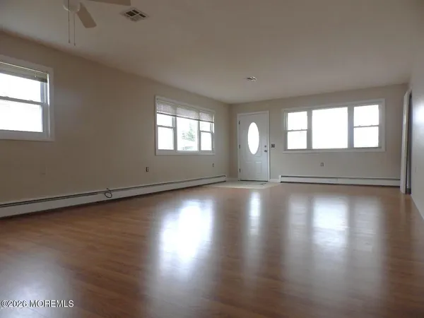 an empty room with wooden floor and windows