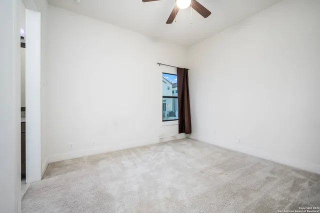 an empty room with a ceiling fan and carpet
