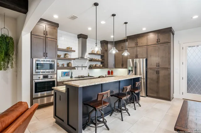 a kitchen with kitchen island a dining table chairs stainless steel appliances and cabinets