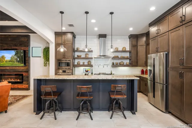 a kitchen with stainless steel appliances kitchen island granite countertop a table chairs refrigerator and microwave