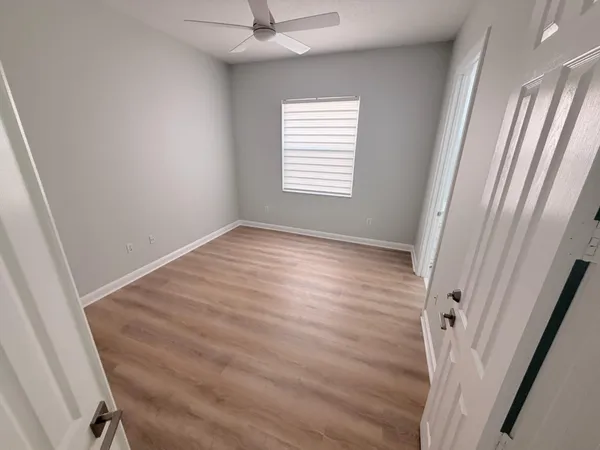 a view of an empty room with wooden floor and a window