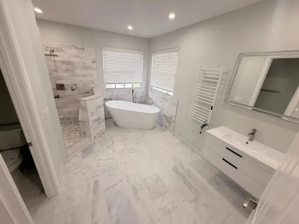 a spacious bathroom with a bathtub sink toilet and mirror
