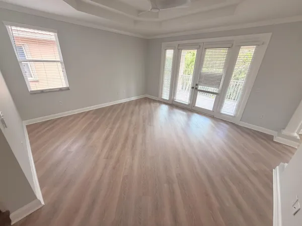 a view of an empty room with wooden floor and a window