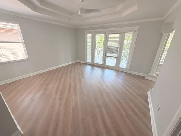 an empty room with wooden floor and windows