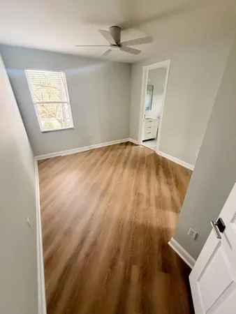 a view of an empty room with wooden floor and a mirror