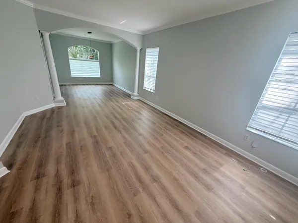 a view of an empty room with wooden floor and a window