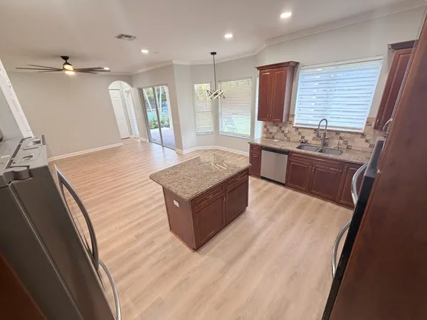 a large kitchen with kitchen island granite countertop wooden cabinets a counter top space and stainless steel appliances